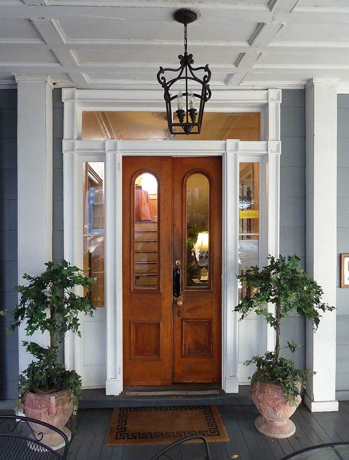 Front entry door of a bed and breakfast decorated with charming potted trees. This symmetrical grouping of plants has a formal elegance that is suitable for traditional, vintage and some transitional style homes. Photo courtesy of Liz West.